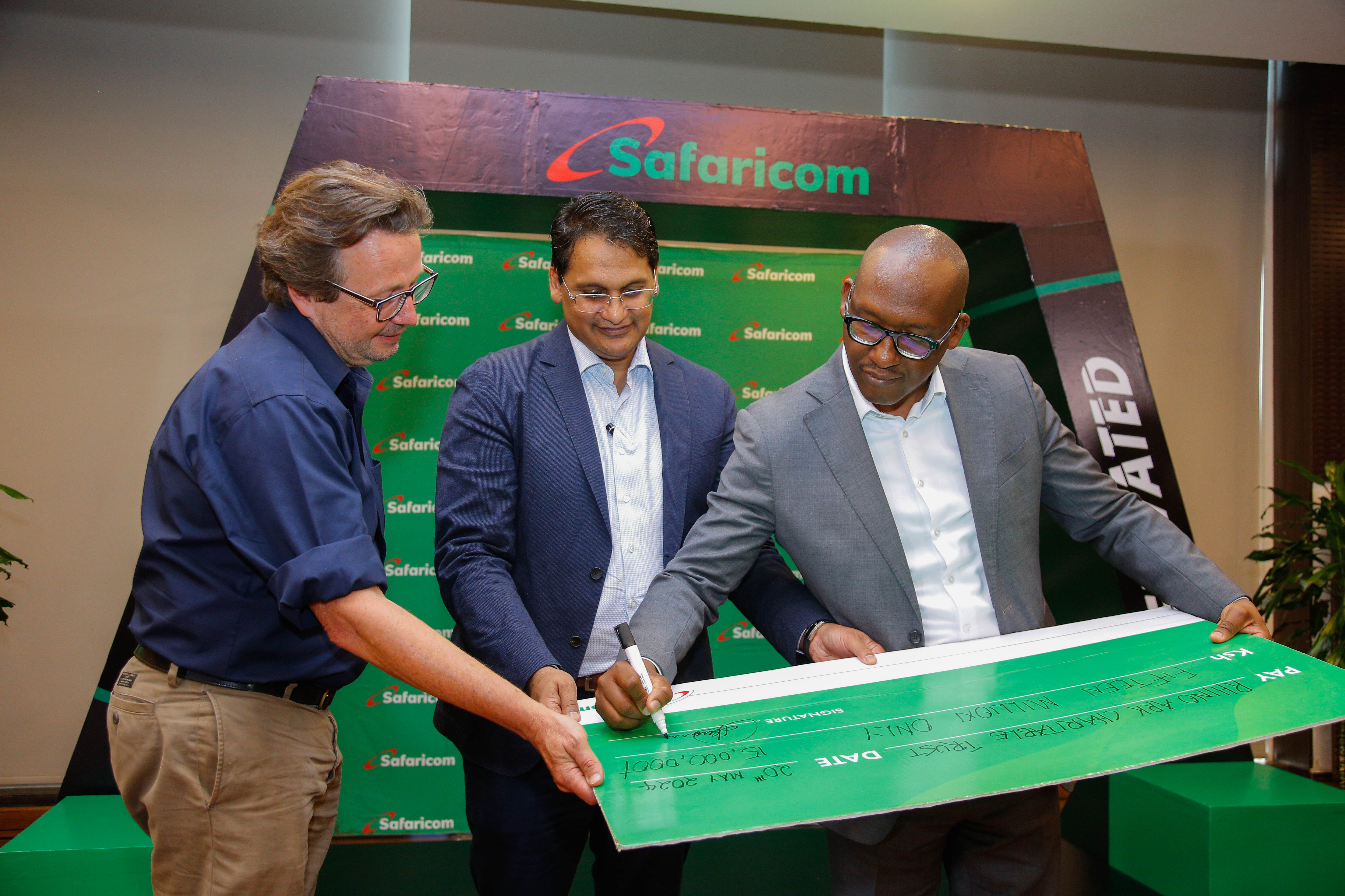 Safaricom Plc Chairman, Adil Khawaja (center) and Rhino Ark Executive Director, Christian Lambrechts (left) witness as Safaricom Acting Chief Corporate Affairs Officer, Fred Waithaka (right) signs a dummy cheque of Ksh. 15,000,000 ahead of the Rhino charge event.